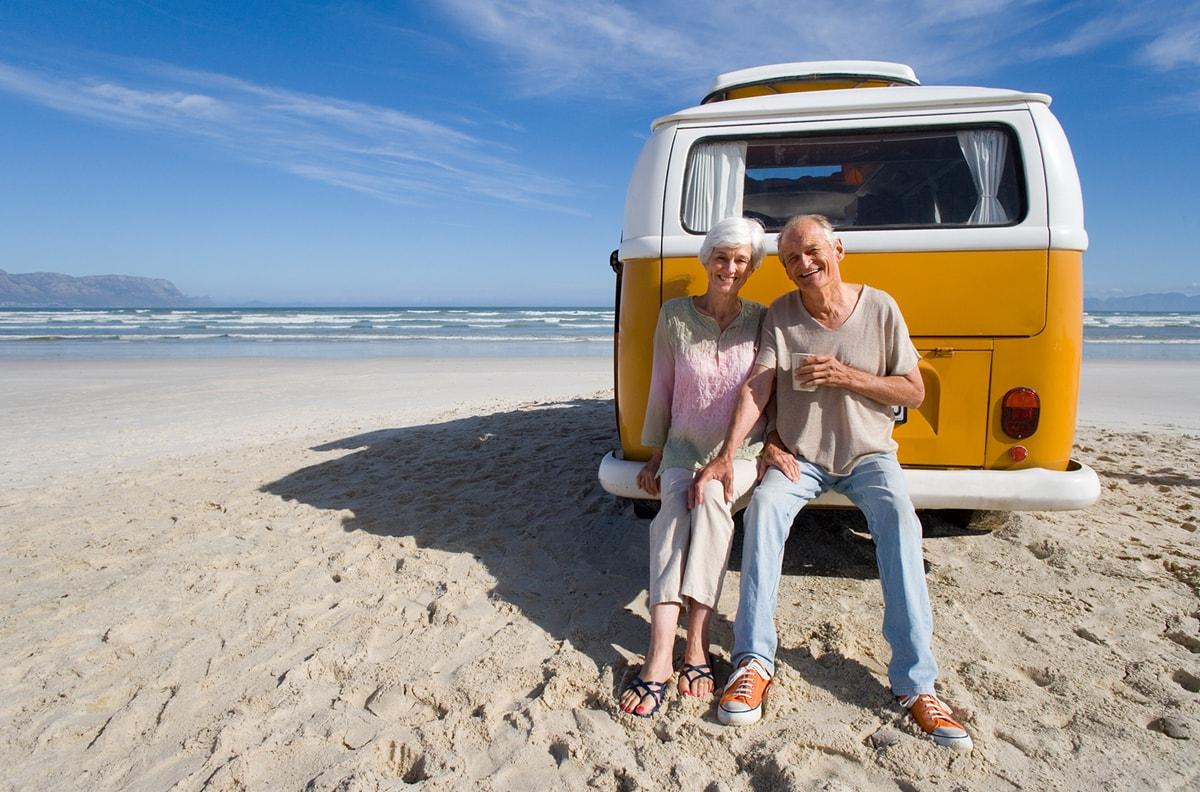 older woman and man sitting on bumper of van